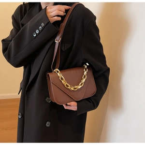 Detail of vintage brown shoulder bag with textured leather and gold chain decoration