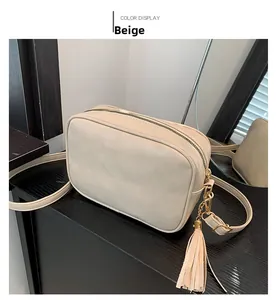 Detail of beige faux leather crossbody bag with long tassel charm and golden zipper