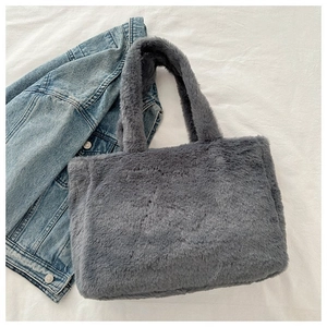 Vue détaillée du sac cabas en fausse fourrure grise posé sur un tissu blanc texturé