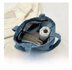 Detail shot showing the large capacity interior of the blue denim tote with zipper pocket