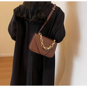 Brown small square bag with crocodile pattern and golden chain strap on a model