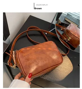 Close-up of brown vintage crossbody bag with soft PU leather texture and tassel detail