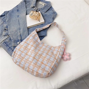 Nahaufnahme der karierten Tweed-Schultertasche mit einem süßen rosa Plüschanhänger