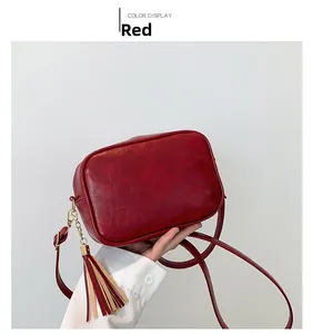 Detail of vintage red crossbody bag with decorative tassels and metallic chain accents