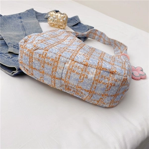 Detail der blau-orange karierten Tweed-Hobo-Tasche mit süßem rosa Plüschblumenanhänger