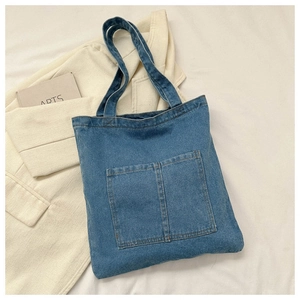 Detailed close-up of blue denim tote bag with dual front pockets and durable canvas texture
