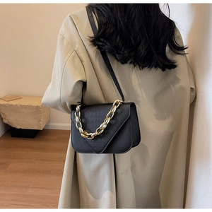 Detail of black square crossbody bag with gold chain and crocodile pattern texture