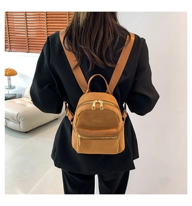 Détail d'un mini sac à dos carré kaki montrant la texture suède et l'étiquette mode