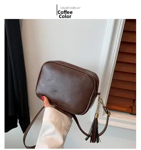 Detail view of coffee brown square crossbody bag with stylish metal tassel accent