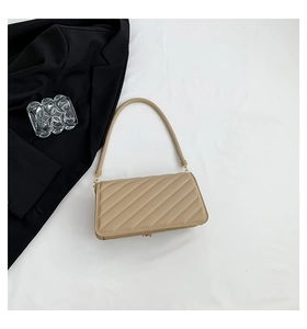 Detail of beige quilted shoulder bag with fine leather strap and gold metal buckles