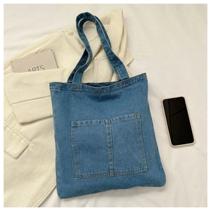 Detailed view of blue denim tote bag with two front pockets and wash texture