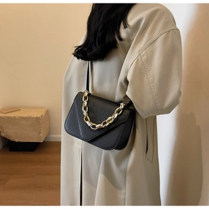Close-up of black crocodile pattern leather bag with thick gold chain strap details