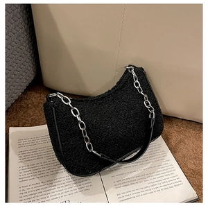 Détail du sac hobo noir en peau de mouton avec chaîne argentée sur un magazine