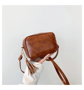 Detail of vintage brown crossbody bag with soft PU leather texture and gold zipper tassel