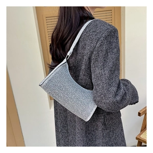 Silberne Glitzertasche mit Metallic-Textur an Modell über einem Wollmantel gezeigt
