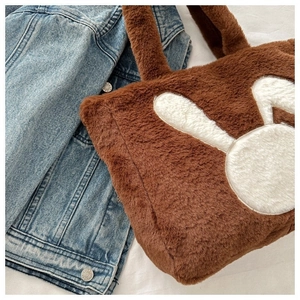 Détail du sac cabas en peluche marron avec patch lapin blanc sur jean bleu clair