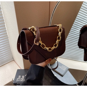 Close-up of deep brown crocodile embossed leather bag with gold chain handle detail