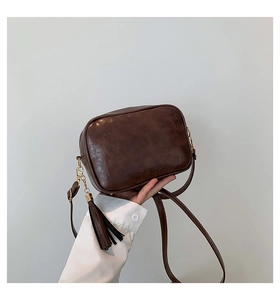 Close-up of vintage brown leather crossbody bag with tassel detail and gold hardware