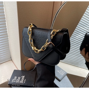 Detail of black crocodile embossed small square bag with gold chunky chain and V-flap design