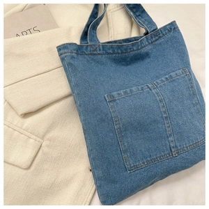 Close-up of blue denim tote bag with front pocket and contrast stitching detail