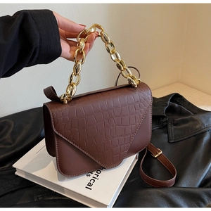 Detail of dark brown faux crocodile flap bag with chunky gold chain handle and strap