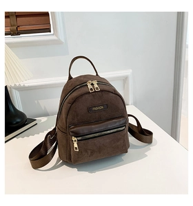 Détail du mini sac à dos en daim marron avec fermetures éclair dorées et logo de mode