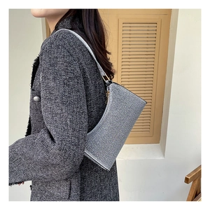 Silberne Pailletten-Halbmondtasche an Model mit klassischem grauem Tweed-Mantel