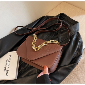 Close-up of dark brown crocodile embossed flap bag with chunky gold chain strap
