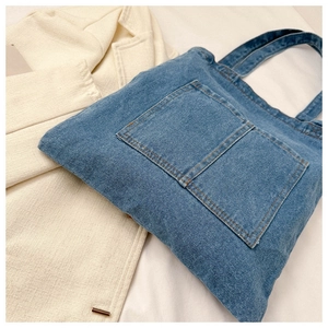 Detail of blue denim tote bag with two front pockets and decorative yellow stitching