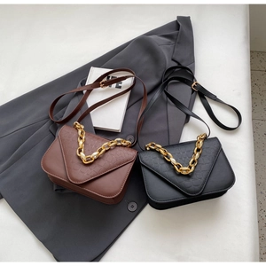 Detailed view of stone-patterned square bags with gold chain handles on grey blazer