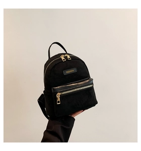 Détail d'un mini sac à dos noir avec texture mate et fermetures éclair dorées