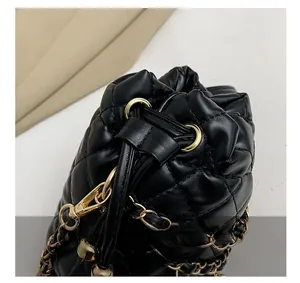 Close-up of black quilted bucket bag with gold chain strap and drawstring detail