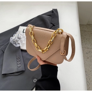Close-up of crocodile embossed beige crossbody bag with chunky gold chain handle