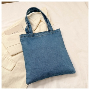 Detailed close-up of dark blue denim tote bag texture and reinforced dual handles