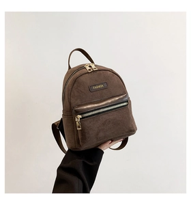 Détail d'un mini sac à dos marron foncé avec texture suédine et zip métallique doré