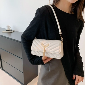 White quilted shoulder bag with gold V-clasp and tassel detail on female model