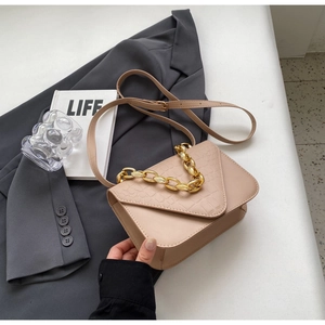 Close-up of minimalist beige stone pattern crossbody bag with gold chain strap