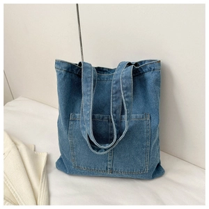 Detail view of heavy washed denim tote bag featuring large front pocket and double straps