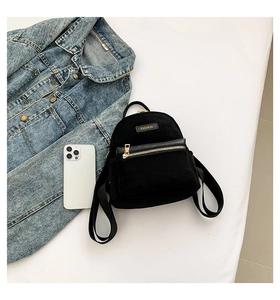 Vue de dessus d'un mini sac à dos noir avec détails dorés à côté d'une veste en jean