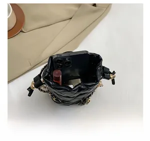 Top view of the interior capacity of a black quilted bucket bag with phone and lipstick