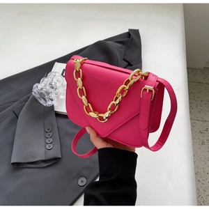 Detail of rose red crocodile embossed faux leather crossbody bag with gold chain strap