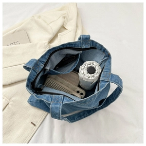 Detail view of the large capacity interior with zipper and blue denim fabric on the tote bag