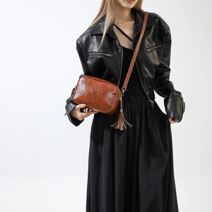 Vintage brown leather crossbody bag with tassel detail on a fashion model in black outfit