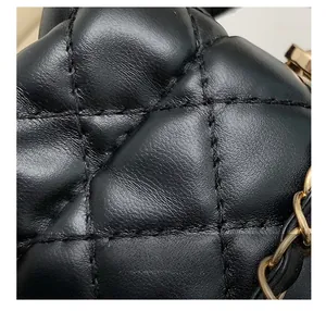 Detailed close-up of black quilted leather texture and gold chain strap on the bucket bag
