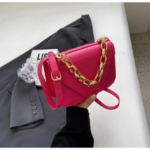 Detail view of pink crocodile embossed handbag with chunky gold chain and long strap