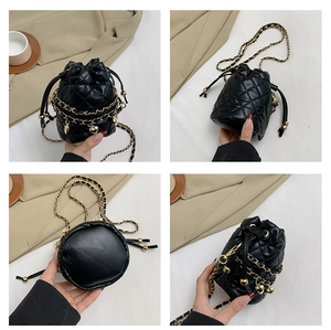 Detail view showing quilted black bucket bag with gold chain and heart charms