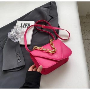 Detail of fuchsia square bag featuring crocodile pattern leather and gold metal chain strap