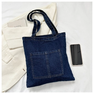 Detail showing deep blue denim tote bag with double front pockets and white contrast stitching