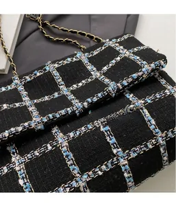 Détail de la texture en tweed noir et de la bandoulière chaîne dorée de ce sac à main