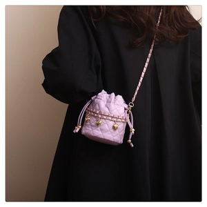 Detail of lavender quilted bucket bag featuring gold heart pendants and chain strap